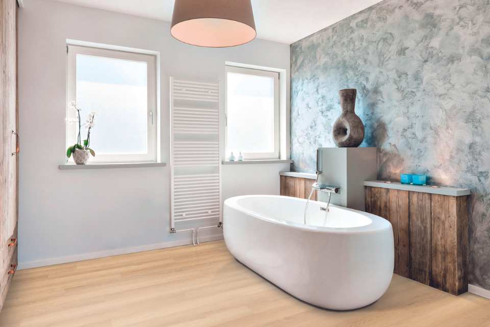 tranquil bathroom with white oak look luxury vinyl, deep soak tub and hand crafted vase